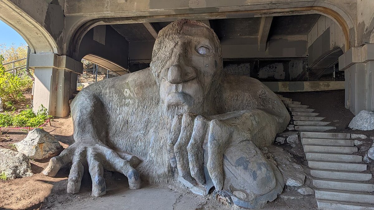 Couple posing near the Fremont Troll sculpture under the Aurora Bridge in Seattle