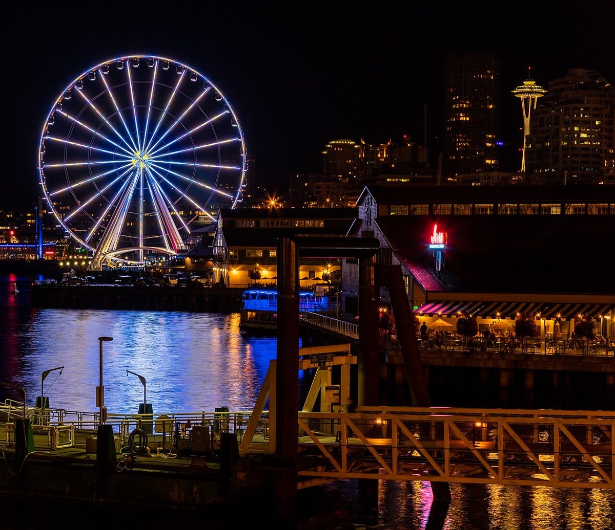 Couple riding an enclosed gondola on the Seattle Great Wheel overlooking Elliott Bay at sunset